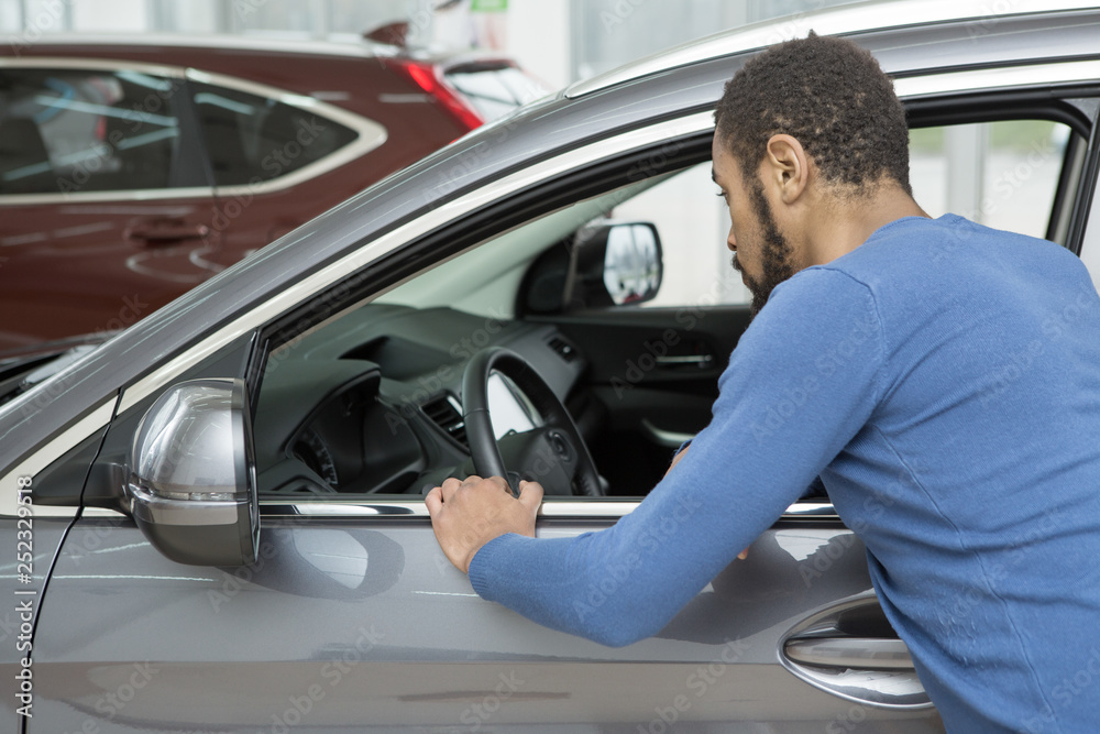 Handsome young African man buying a new automobile at the dealership Handsome young African man buying a new automobile at the dealership