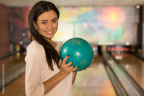 Beautiful young woman posing with a ball at the bowling club