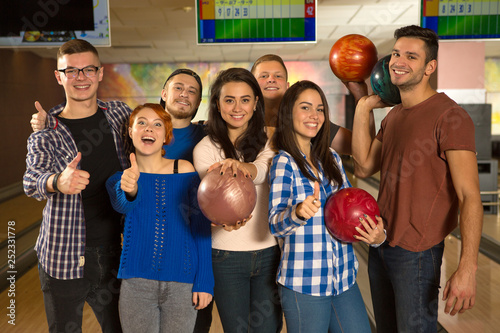 Young happy friends enjoying bowling together