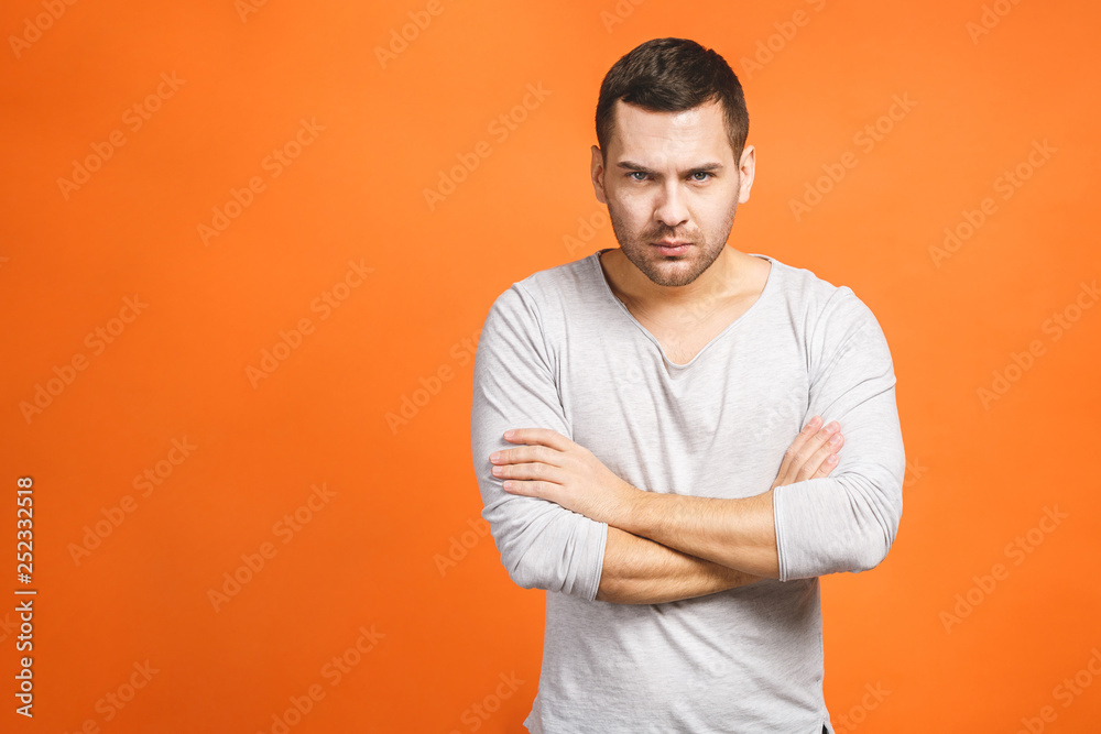 Image of angry displeased man standing isolated over orange background wall. Looking at camera. Image of angry displeased man standing isolated over orange background wall. Looking at camera.