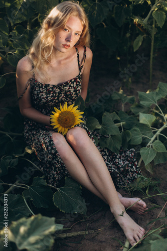 Beauty joyful blondie teenage girl with sunflower enjoying nature and laughing on summer sunflower field. Sunflare, sunbeams, glow sun photo