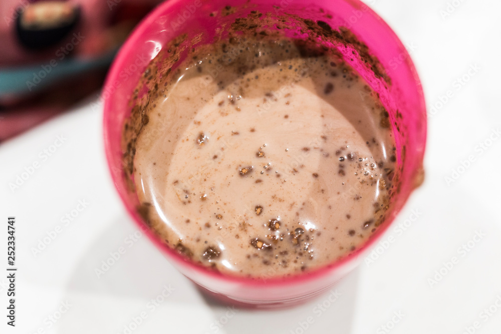 Baby breakfast Cocoa with milk prepared on a pink plastic glass on a white background Baby breakfast Cocoa with milk prepared on a pink plastic glass on a white background