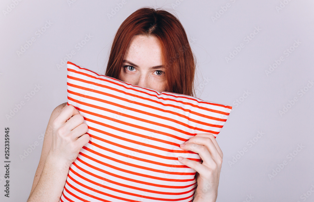 Close up portrait of expressive excited positive joyful happy caucasian girl with stripped pillow in hands Close up portrait of expressive excited positive joyful happy caucasian girl with stripped pillow in hands