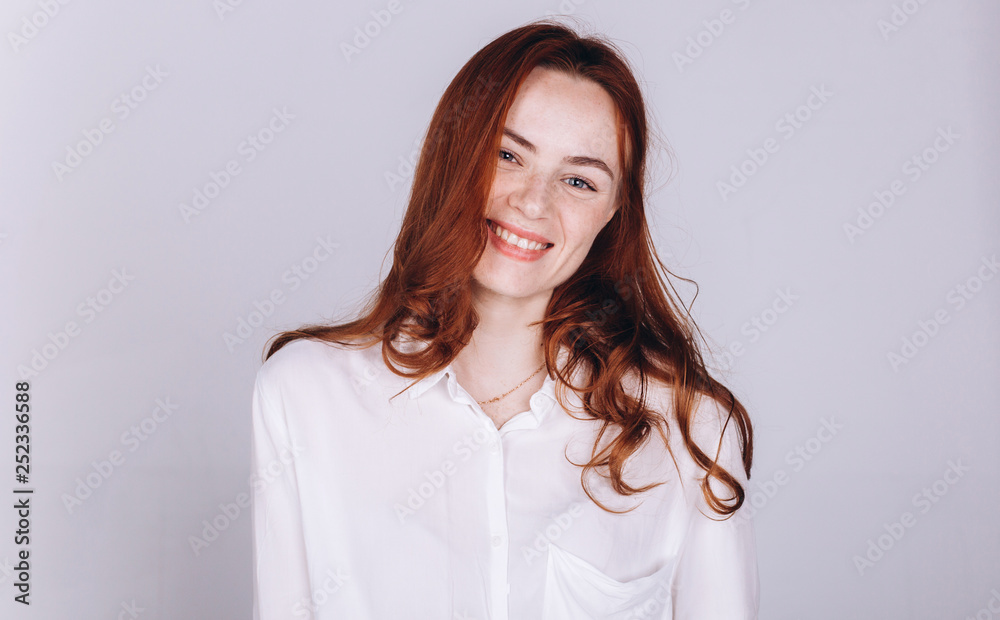 Close up portrait of young ginger pretty emotional caucasian girl with freckles posing in studio on grey background. Beauty, casual, fashion concept Close up portrait of young ginger pretty emotional caucasian girl with freckles posing in studio on grey background. Beauty, casual, fashion concept