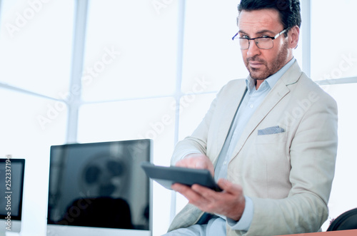 businessman holding a calculator while sitting at his Desk