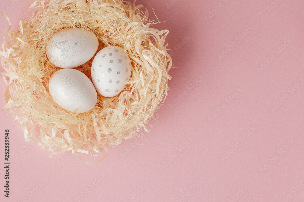 White Easter eggs in a nest on pink background. Design pastel tone in minimal flat lay White Easter eggs in a nest on pink background. Design pastel tone in minimal flat lay