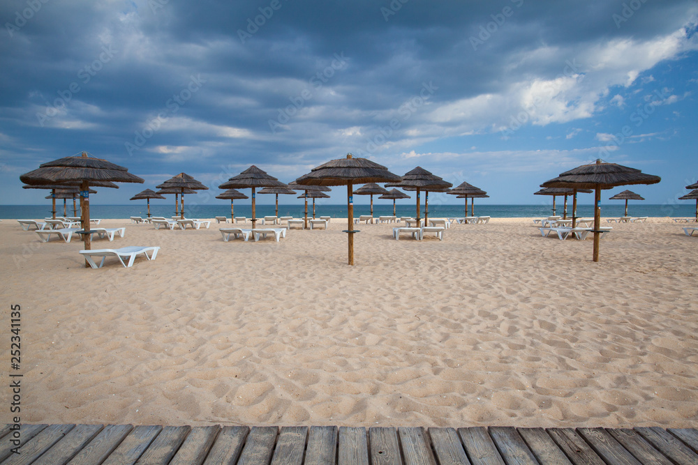 Different parasols and sun loungers on the empty beach on Tavira island, Algarve. Portugal