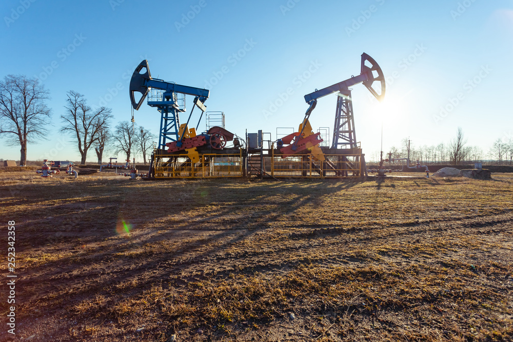 Fototapeta premium oil production tower while working in backlight against a blue sky
