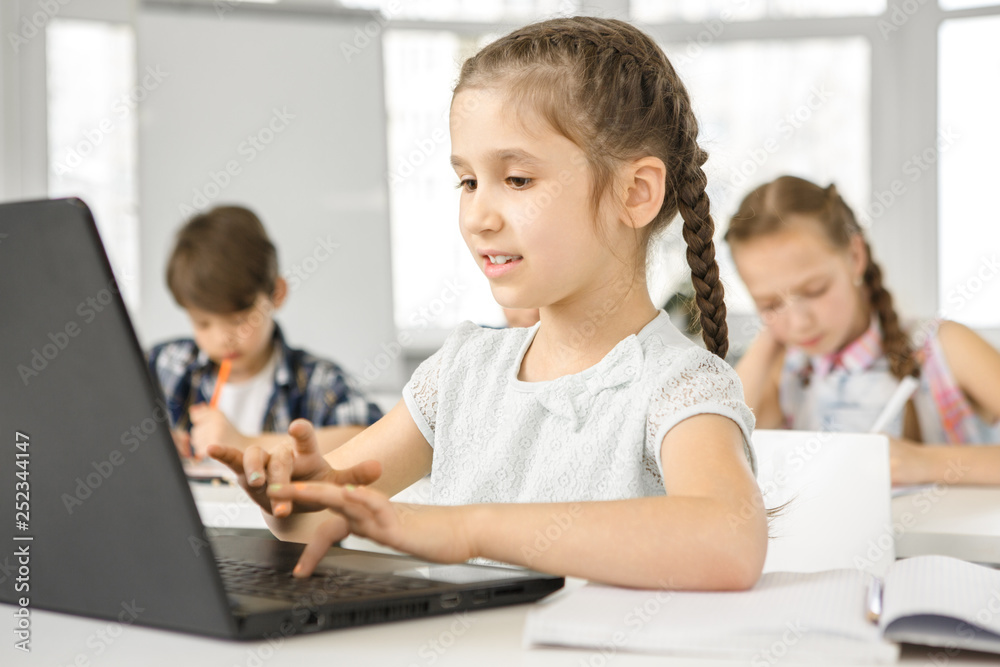 Little cute girl using laptop at school lesson Little cute girl using laptop at school lesson