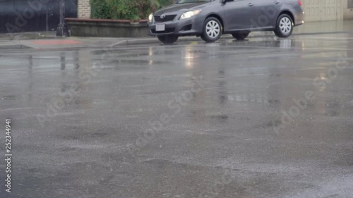 Cars drive across wet roads in a winter rain storm 