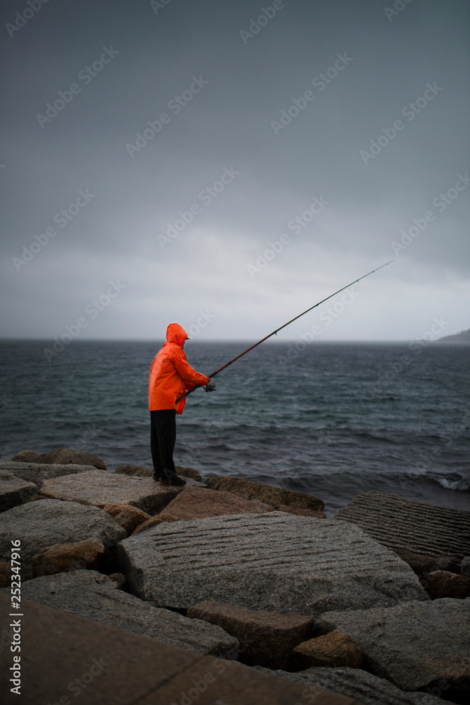 fisherman with flashy raincoat fishing in the rain