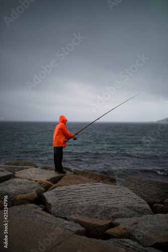 fisherman with flashy raincoat fishing in the rain