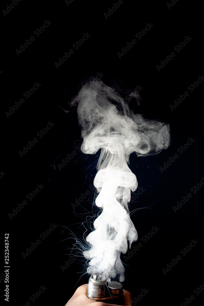 Male hand holds vape without atomiser. Column of vape clouds splash from coil on black background. Fog is white. Stock isolated white smoke with spray boiling glycerine. Male hand holds vape without atomiser. Column of vape clouds splash from coil on black background. Fog is white. Stock isolated white smoke with spray boiling glycerine.