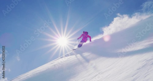 Skier doing amazing powder turns in slow motion backlit, epic backcountry ski adventure holiday photo