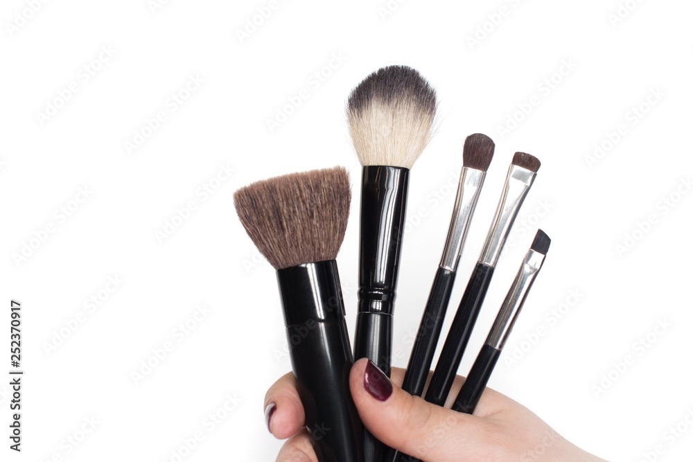 young woman holding black makeup brushes on white background young woman holding black makeup brushes on white background