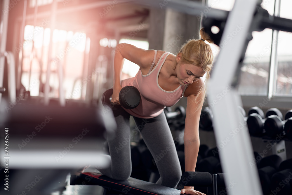 Strong woman doing exercises with dumbbells in gym Strong woman doing exercises with dumbbells in gym
