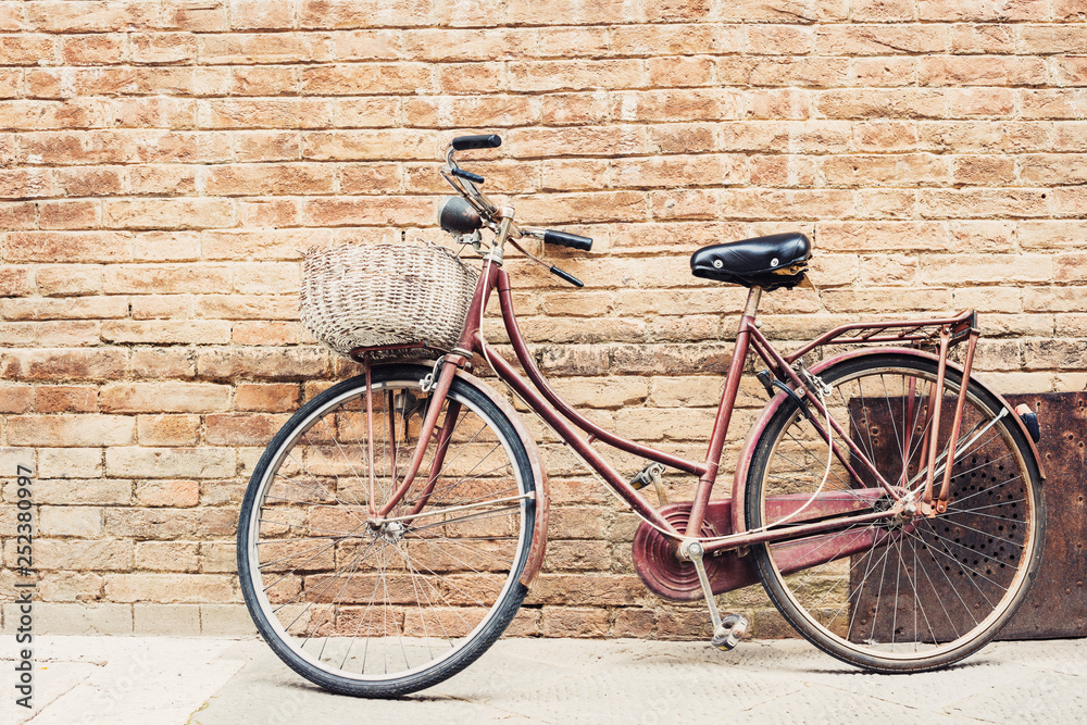 Fototapeta premium Old bicycle with a basket leaning against a wall 