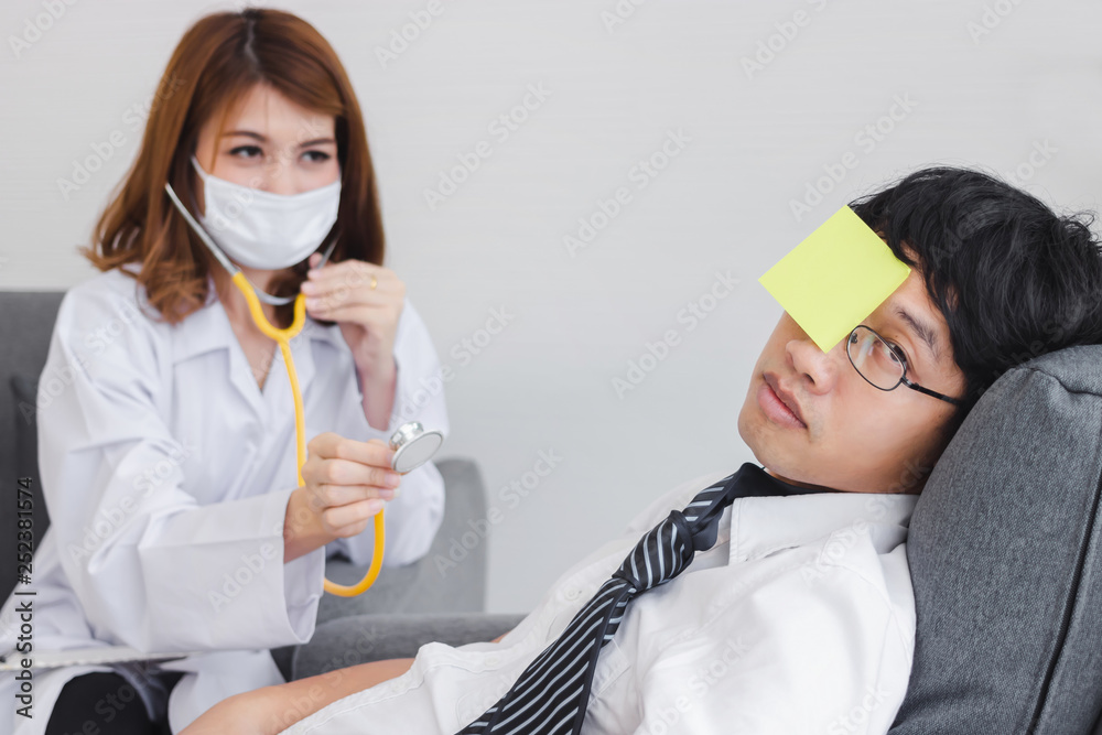 Young Asian female doctor with clipboard diagnosing disabled overworked business man