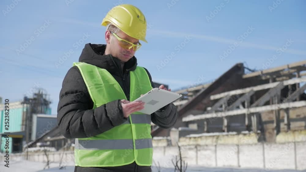 Engineer in hard hat is using a tablet computer in a industry factory. Engineer in hard hat is using a tablet computer in a industry factory.