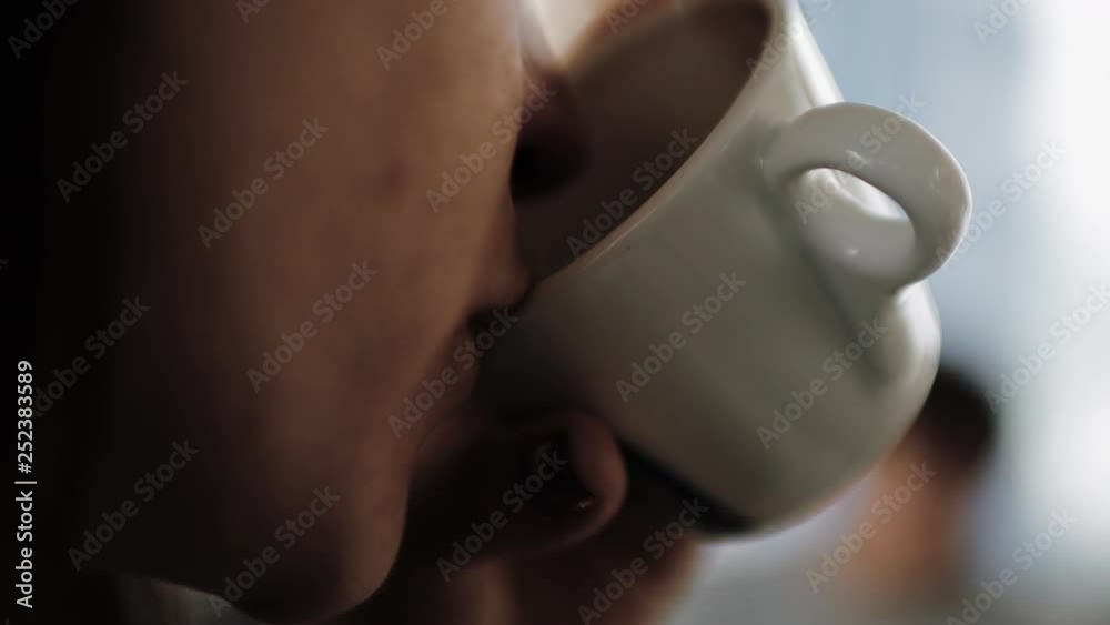 Young beautiful girl in a hat with a cup of coffee in hand and drinking it.