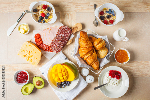 Continental breakfast table with croissants, jam, ham, cheese,  butter, granola and fruit.
