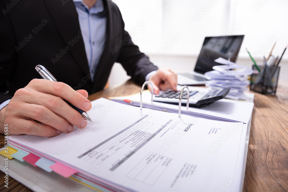 Businessperson Calculating Invoice With Calculator Businessperson Calculating Invoice With Calculator