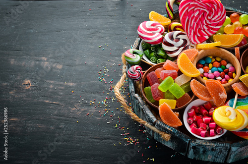Colorful candies, jelly and marmalade in a wooden box. Sweets. On the old background. Top view. free copy space.