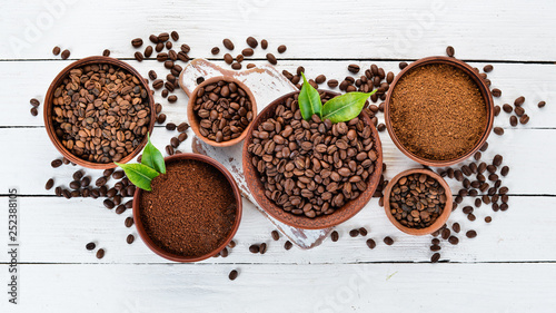 Ground coffee and coffee beans. On a white wooden background. Top view. Free space for your text.