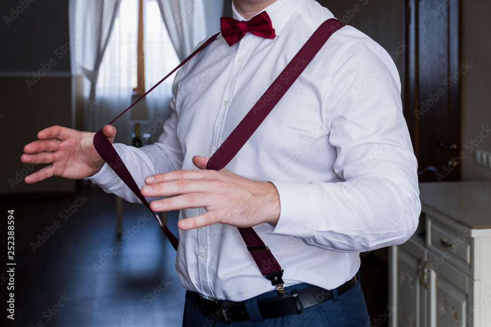 Naklejka premium the groom holds his hands suspenders in a suit