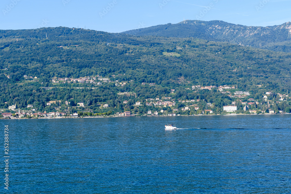 Scenic view of beautiful Garda Lake, with a little boat and Italian villages in the background