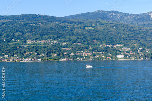Scenic view of beautiful Garda Lake, with a little boat and Italian villages in the background © Cristina Ionescu