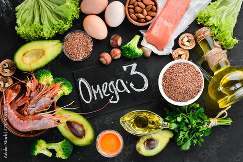 Food with natural vitamin Omega 3. Healthy food: fish, shrimp, broccoli, flax, nuts, egg, parsley. Top view. Free space for your text. On a black background. photo