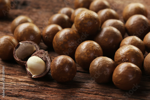 Roasted macadamias on wooden table, selective focus and toned image. Healthy food concept, free space for text.