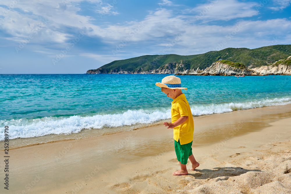 Toddler boy wearing straw hat walking on beach Toddler boy wearing straw hat walking on beach