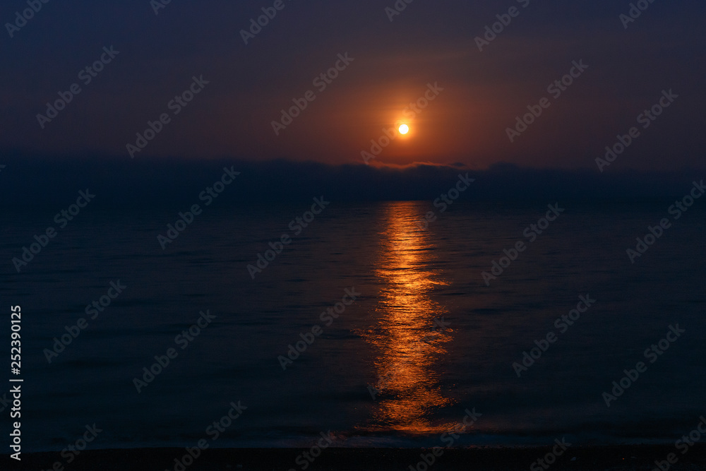 Moon goes down in the sea at the early morning