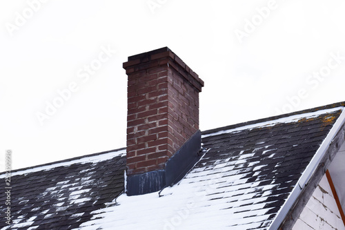 Wallpaper Mural Brown brick chimney on grey asphalt shingles roof partly covered with snow in winter against sky with copy space for text. Torontodigital.ca