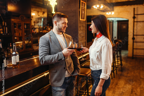 Man and woman drinks red wine at bar counter