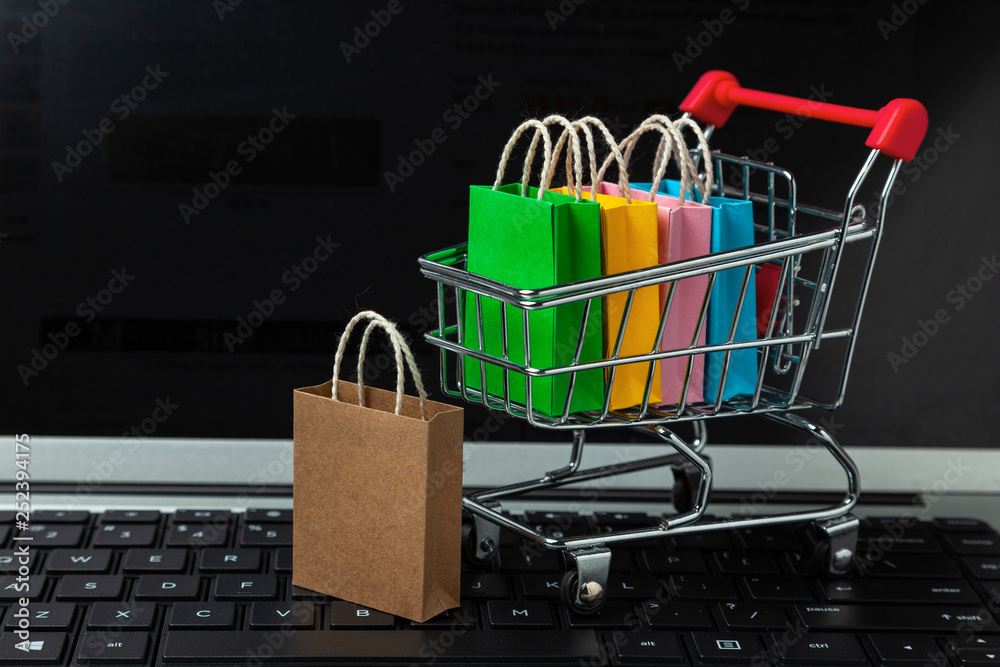 Buying goods and clothing in the online store. Shopping bags in shopping  cart on laptop keyboard Stock Photo | Adobe Stock