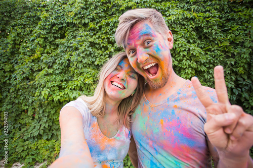 Photography Festival of holi and technology concept - young couple making selfie at the fest