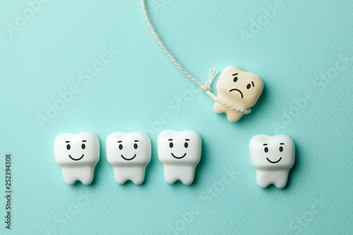 Tableau sur toile Healthy white teeth are smiling and the removal of the baby tooth with rope is sad on green mint background