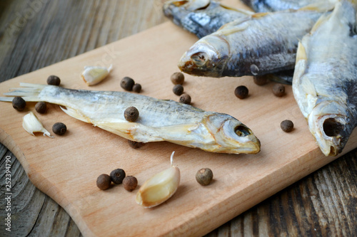 Salty stockfish cod on wooden board with gaarlic and pepper