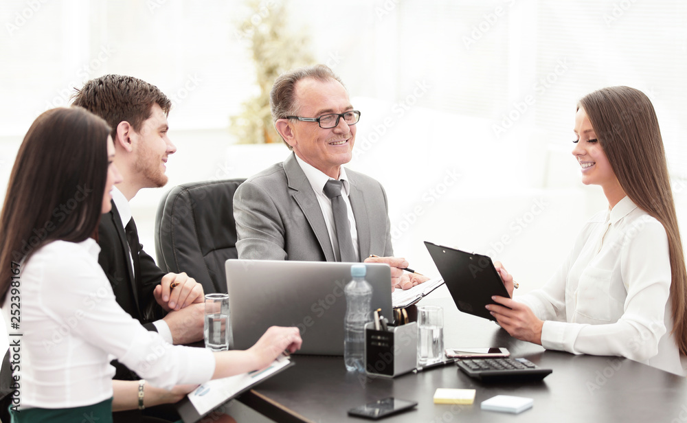 Manager discussing work issues with his assistants behind a Desk Manager discussing work issues with his assistants behind a Desk