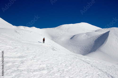 Snow covered mountains and ski mountaineers along sunny trail. Slovenia, Julian Alps, Komna. There are is snowshoeing and ski touring paradise. photo