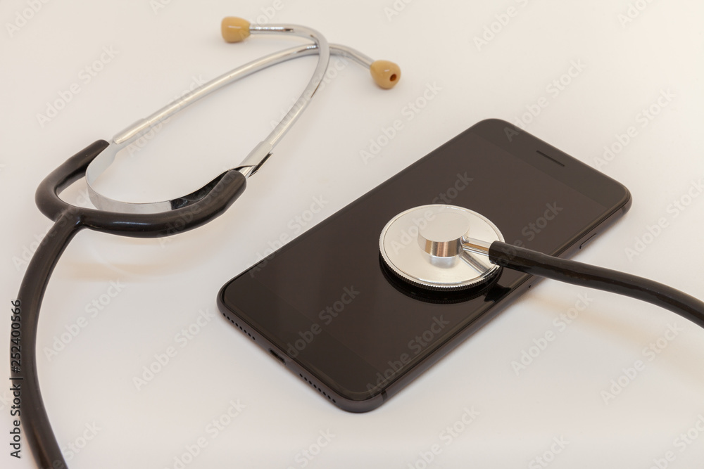 stethoscope is leaning against the screen of a black smartphone