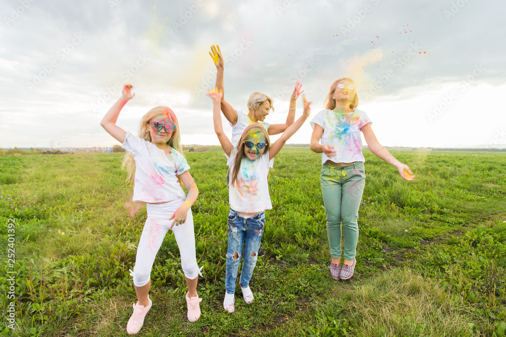 Holiday, festival holi and friendship concept - Jumping happy women and children covered in paint Holiday, festival holi and friendship concept - Jumping happy women and children covered in paint