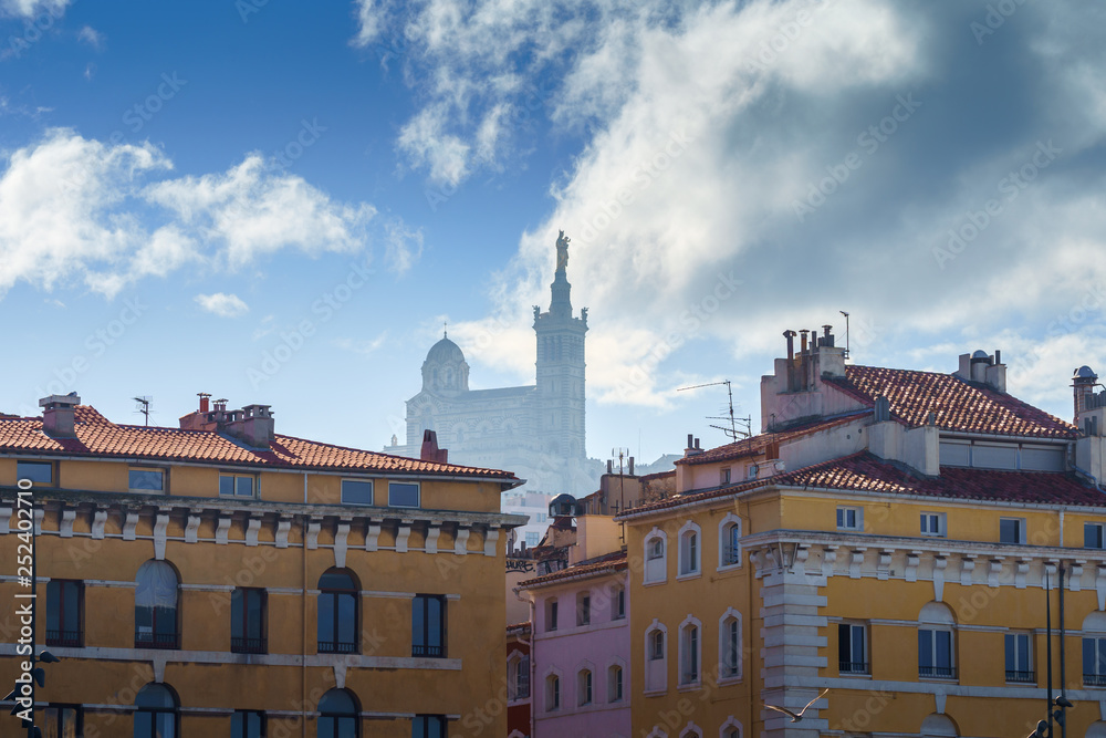 Basilique Notre-Dame de la Garde in the foggy background with red tiled roof Marseille houses