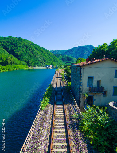 Railway that runs along the blue lake in the green mountains