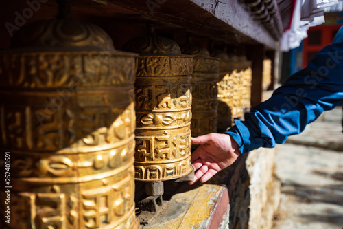 Nepal. Everest trekking. Tibetan prayer wheels in Boudhanath. Hand turns the wheel. On wheels hieroglyphs - prayers in Nepali. Auṃ maṇi padme hūṃ - jewel in the lotus. photo