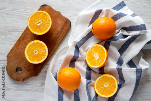 Bilde på lerret Halved and whole oranges on white wooden background, top view