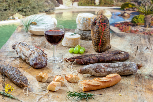 Fototapeta Naklejka Na Ścianę i Meble -  Corsican specialities appetizer: delicatessen, and cheese made in Corsica over a swimming pool panorama background, with a glass of wine